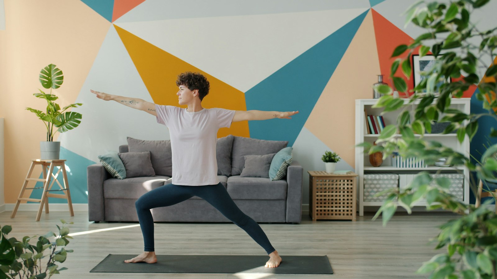 A woman following a yoga teacher on a tablet at home